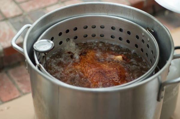 Turkey frying in pot with thermometer outside on patio